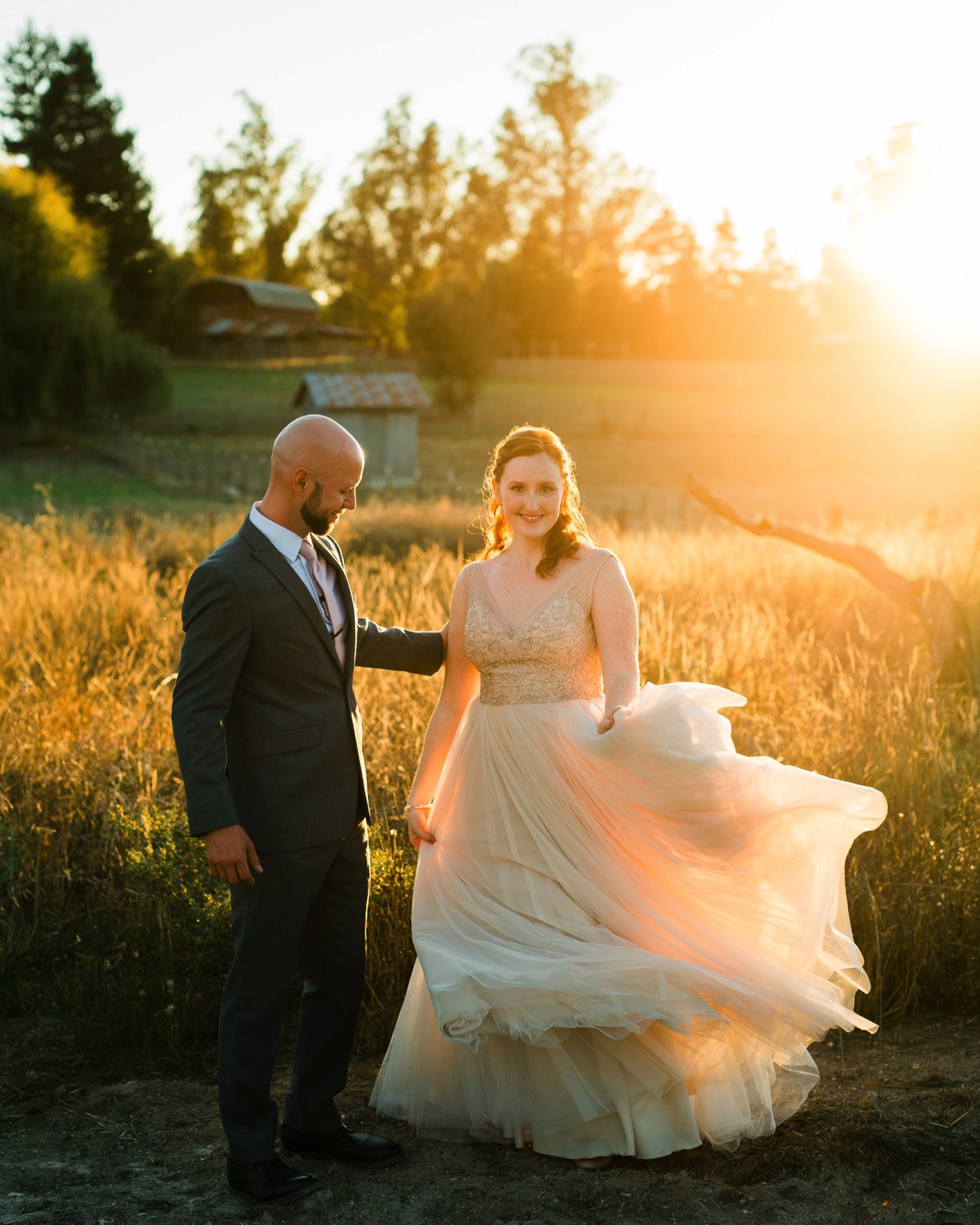 bride twirling at sova gardens in her dress while groom watches at sunset