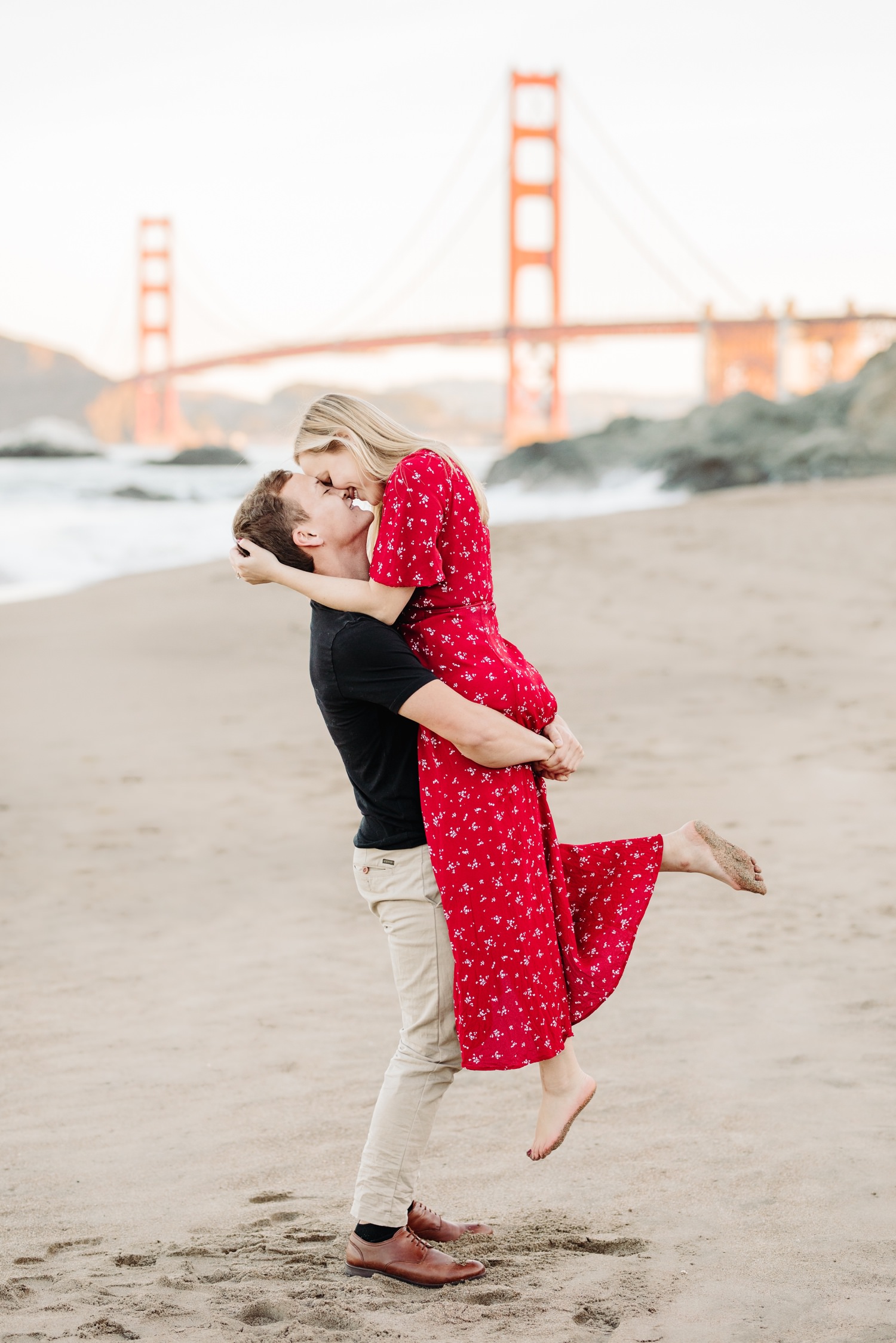 couple embracing in front of golden gate bridge at their engagement session at sunrise in california