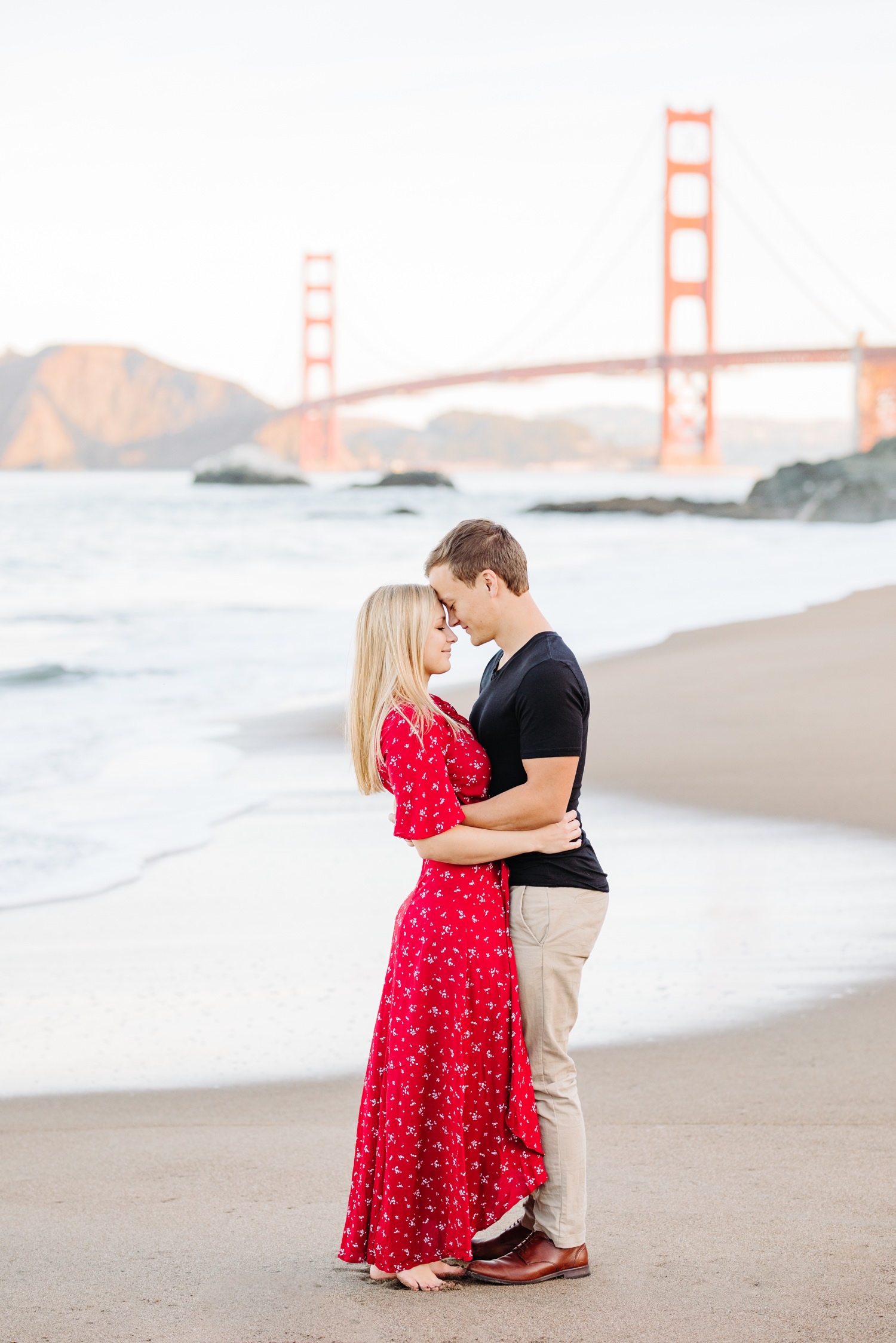 couple hugging at their sunrise engagement session on bakers beach in san francisco