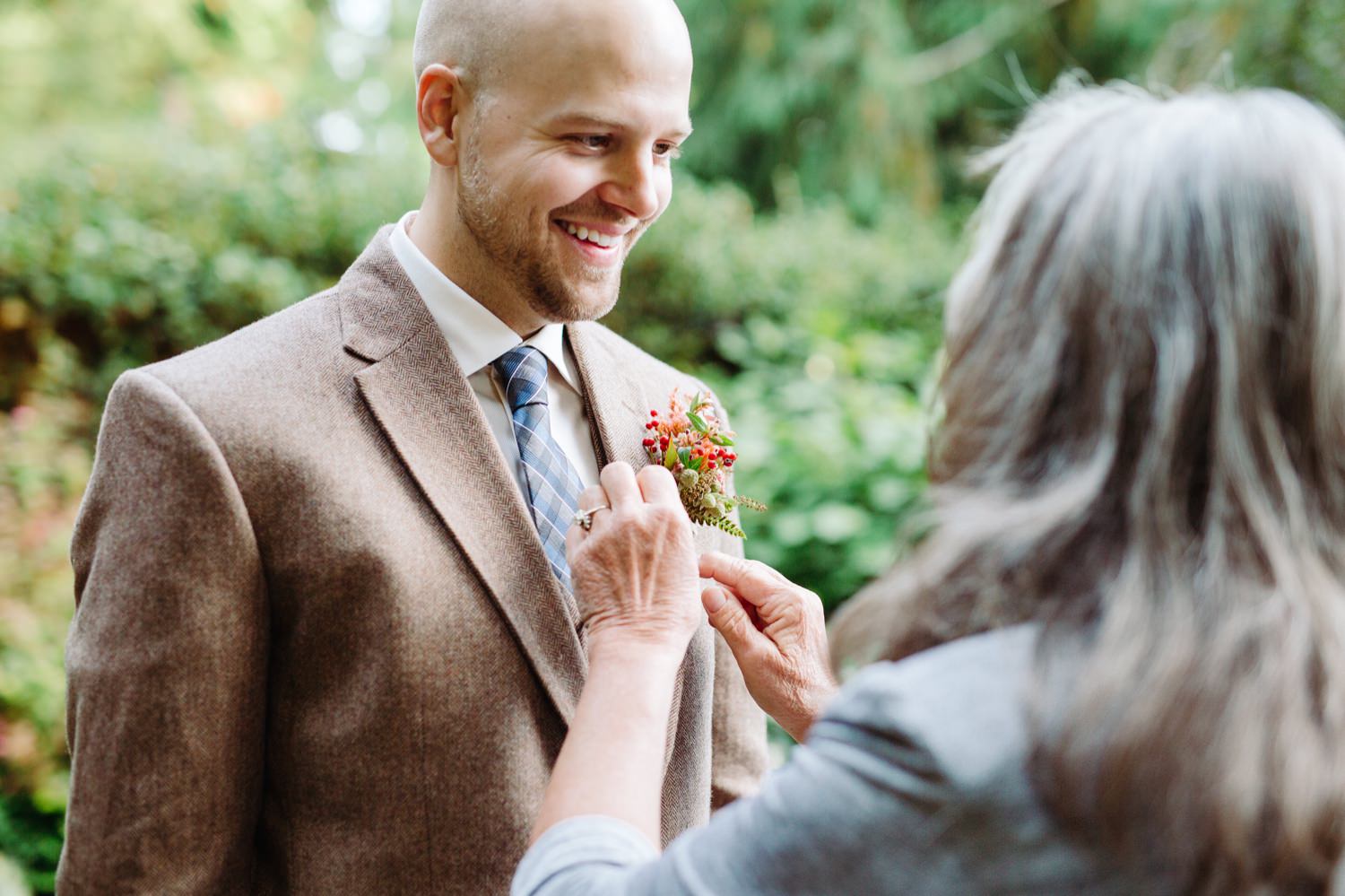mother of the groom pinning the boutonniere on the groom at a wedding at fireseed catering wedding venue