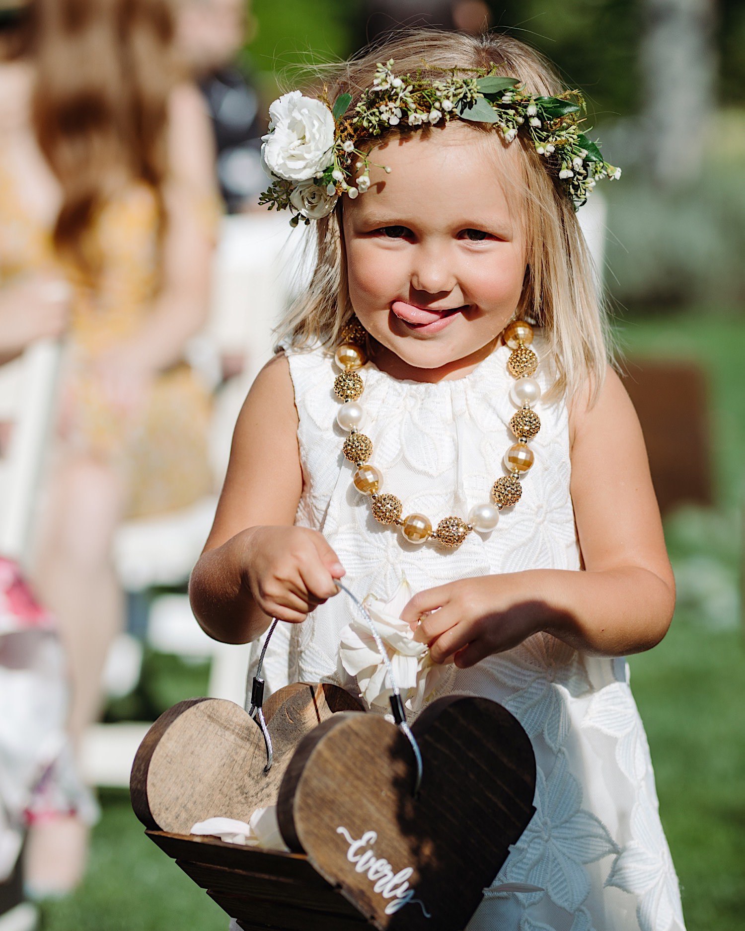 cute flower girl sticking out her tongue walking down the aisle at at wedding ceremony
