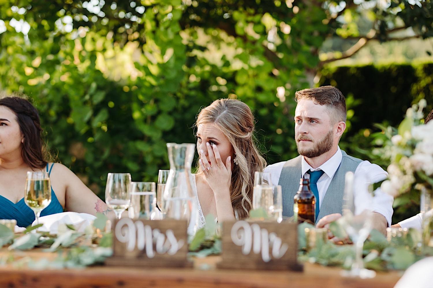 wedding couple listening to speeches during dinner outdoors at Pine Creek Farms and Nursery