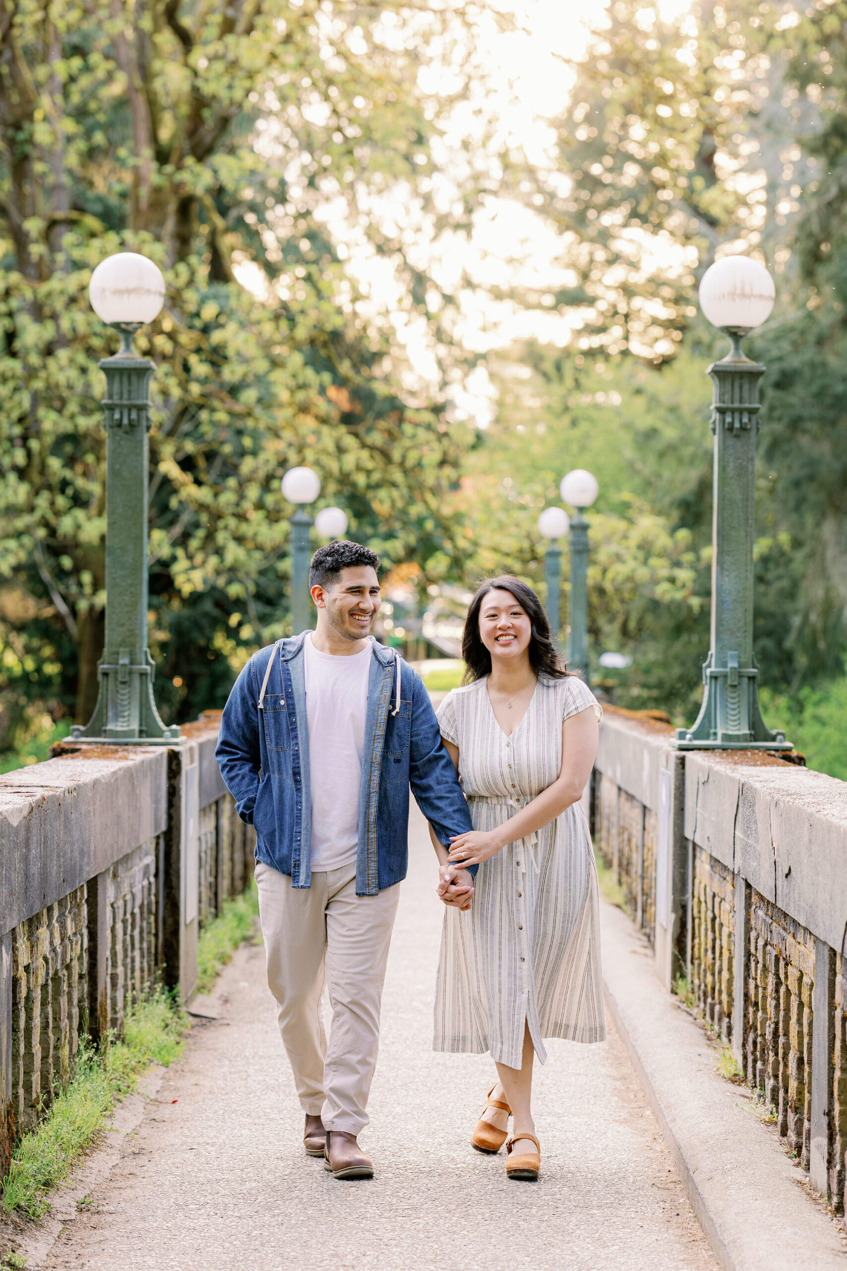 A couple smiles and walks over a pedestrian bridge at Washington Park Arboretum in Seattle.