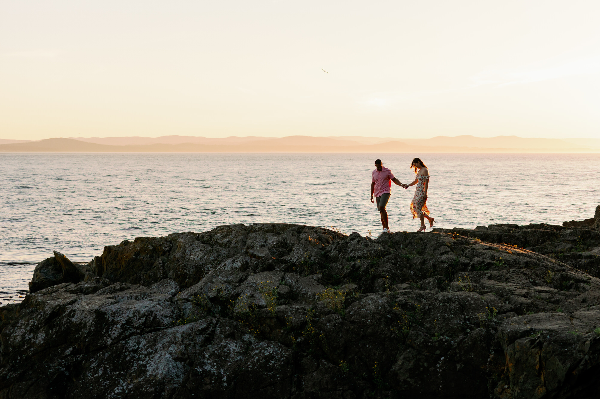 Couple walks along the rocky shoreline at Lime Kiln State Park on San Juan Island.