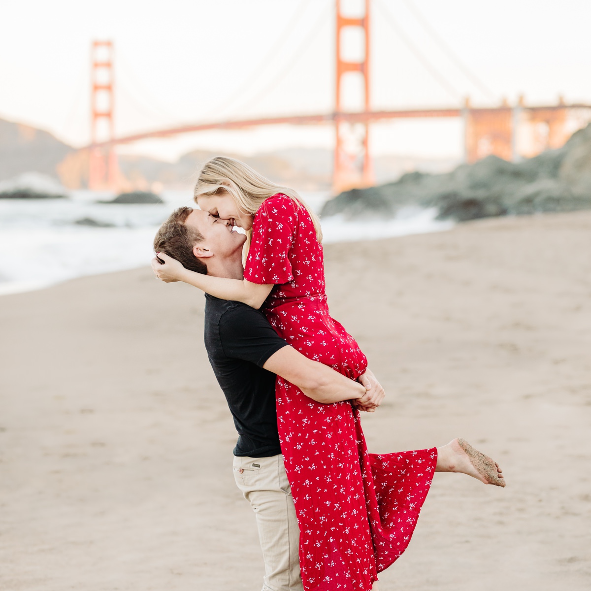 engaged couple embracing in front of the golden gate bridge in san francisco california