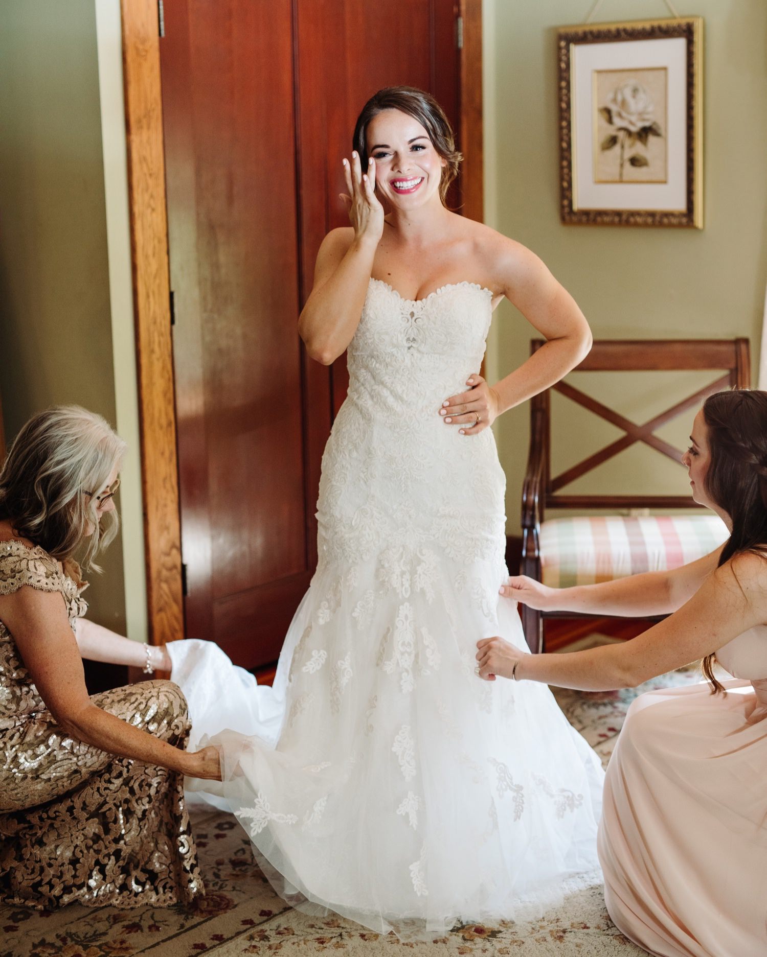 bride in her wedding dress with mom and sister helping