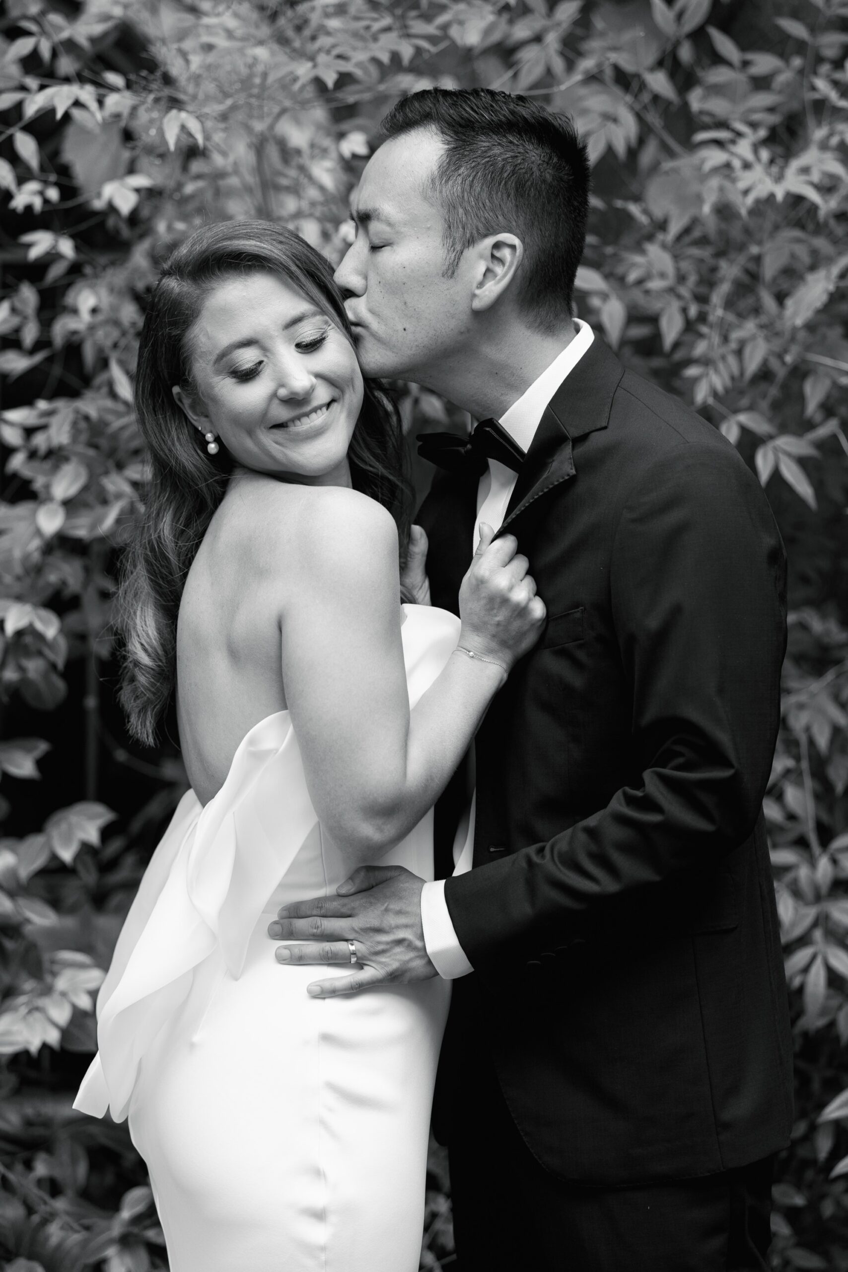 A groom kisses his bride on the temple during their wedding portraits.