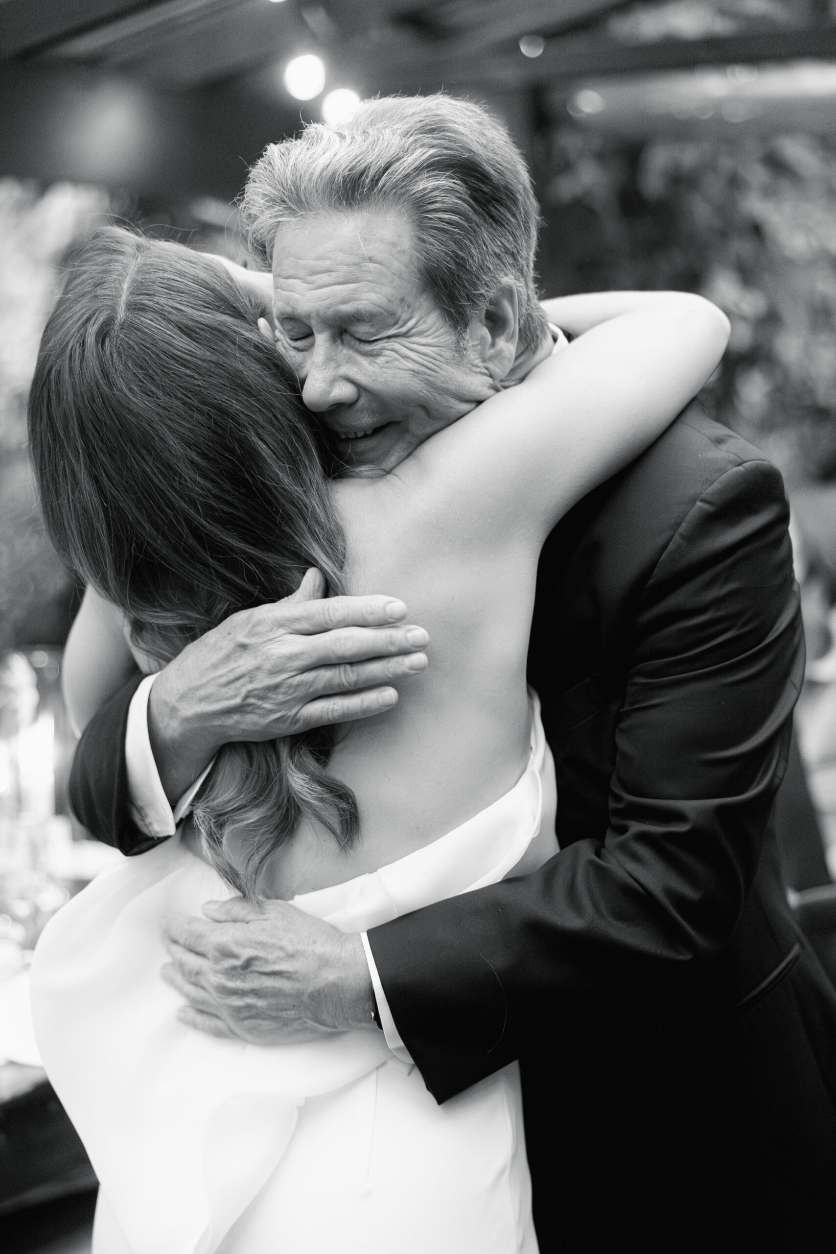 The bride's father hugs the bride after giving an emotional wedding speech.