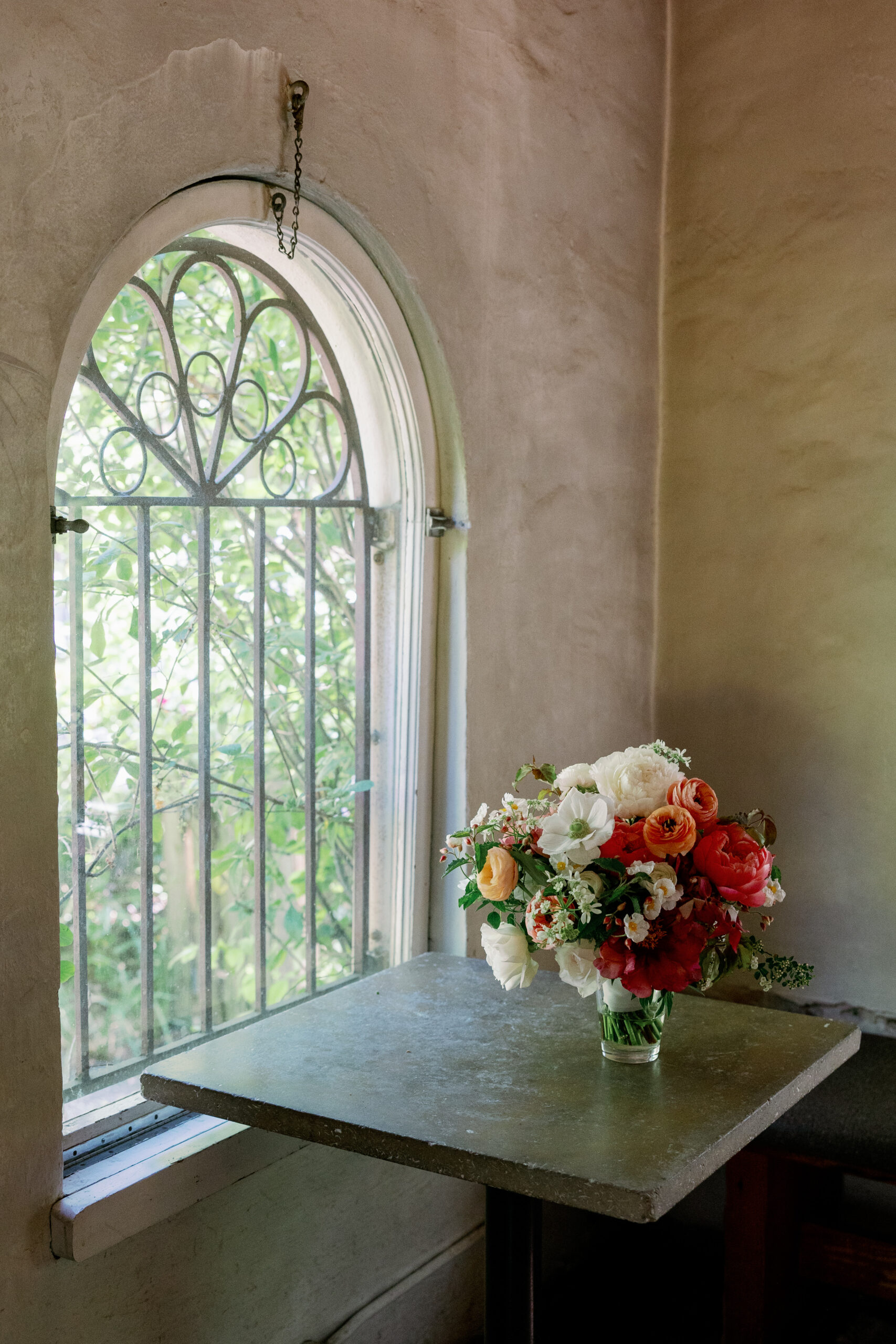 A bouquet sits on a table next to an arched window in the Corson Building.