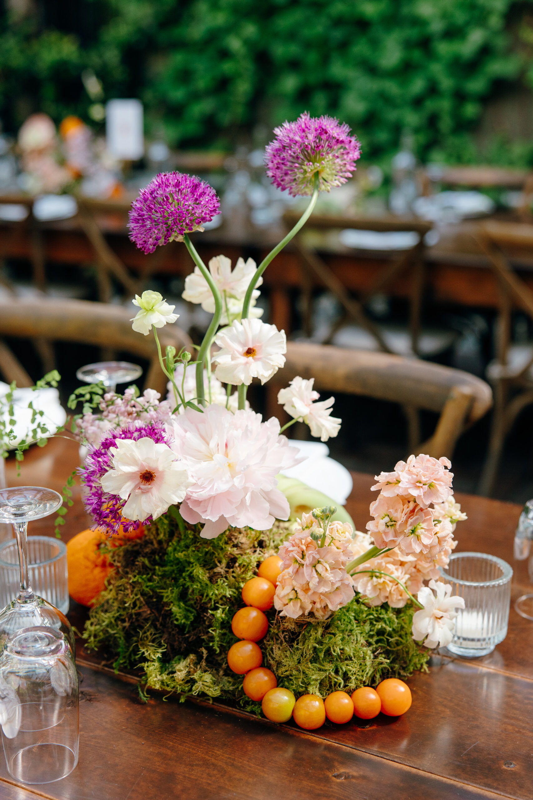 A colorful centerpiece with flowers and tomatoes.
