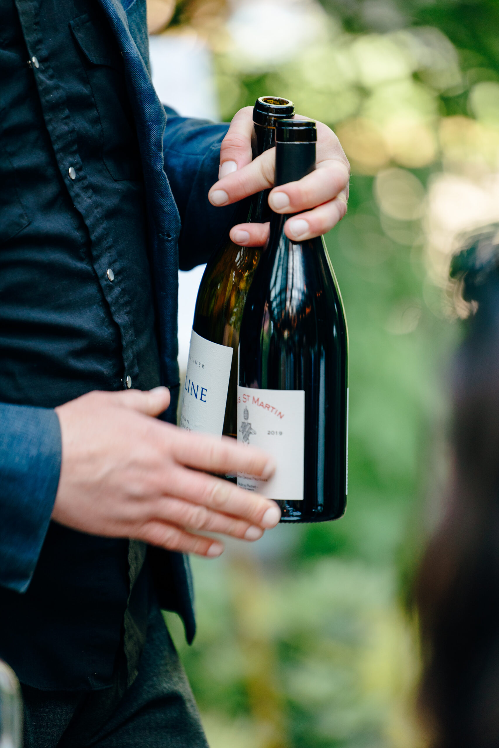 Closeup of a server holding two bottles of wine.