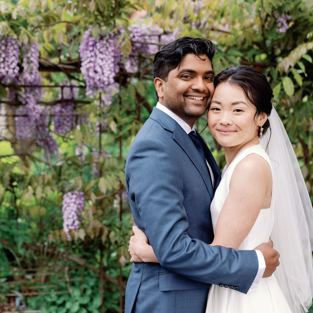 Bride and groom embracing under a canopy of flowers