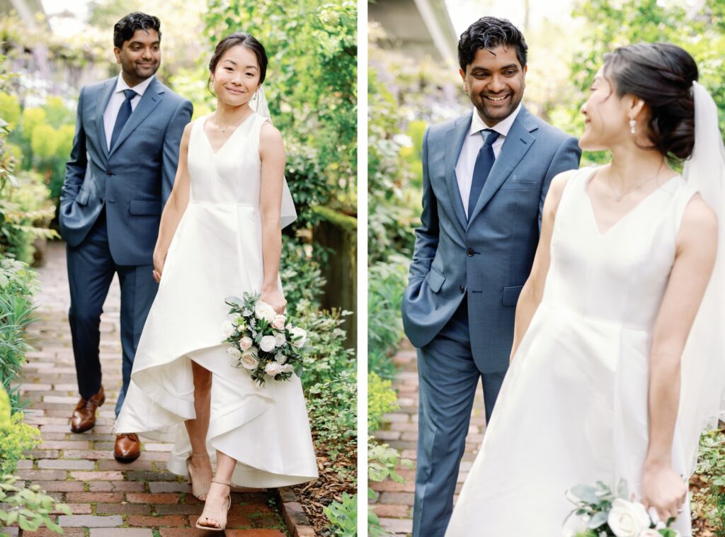 The bride and groom walking down a garden path, smiling at each other.