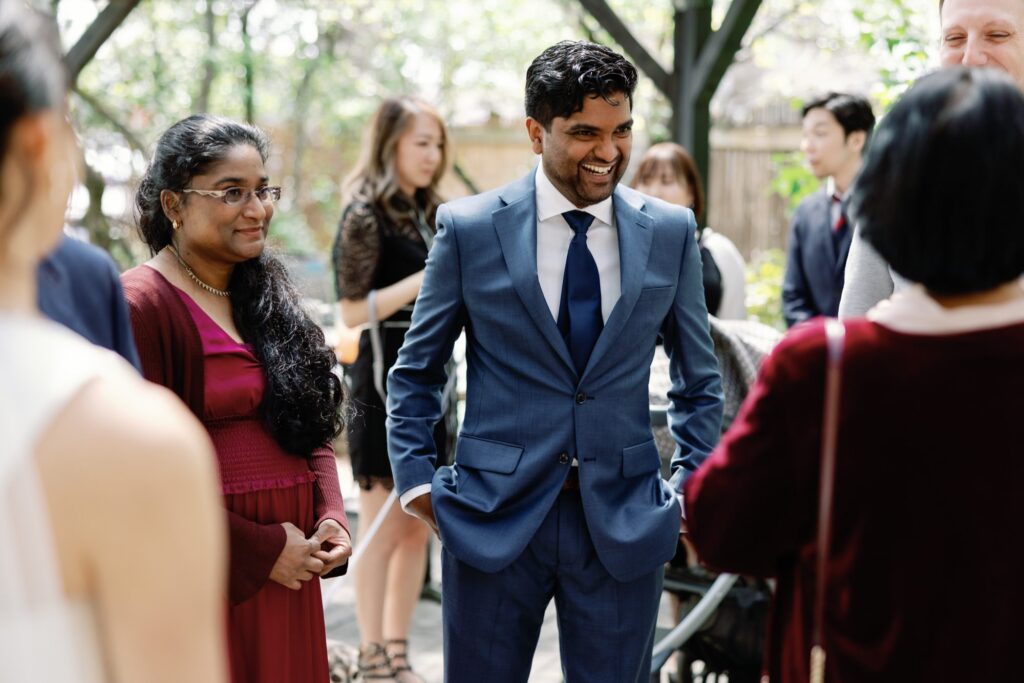 Groom smiling and chatting with guests in an outdoor reception area, capturing the joy of the celebration.