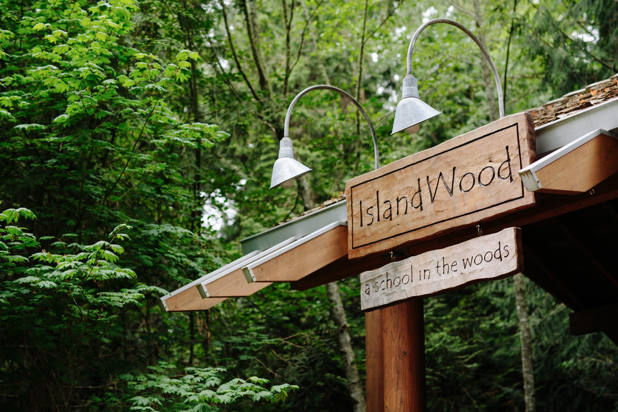 Entrance sign of IslandWood, surrounded by lush green trees