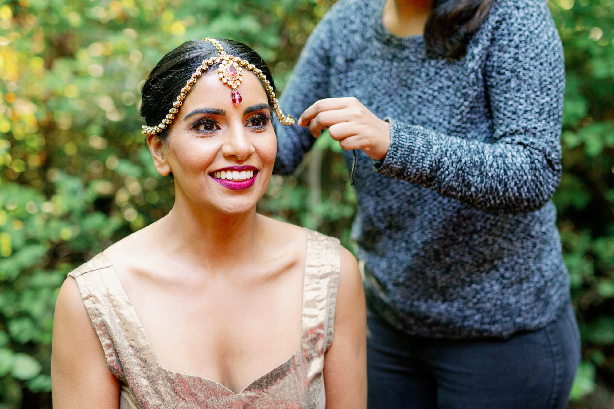 Bride getting ready with help from a friend, smiling brightly