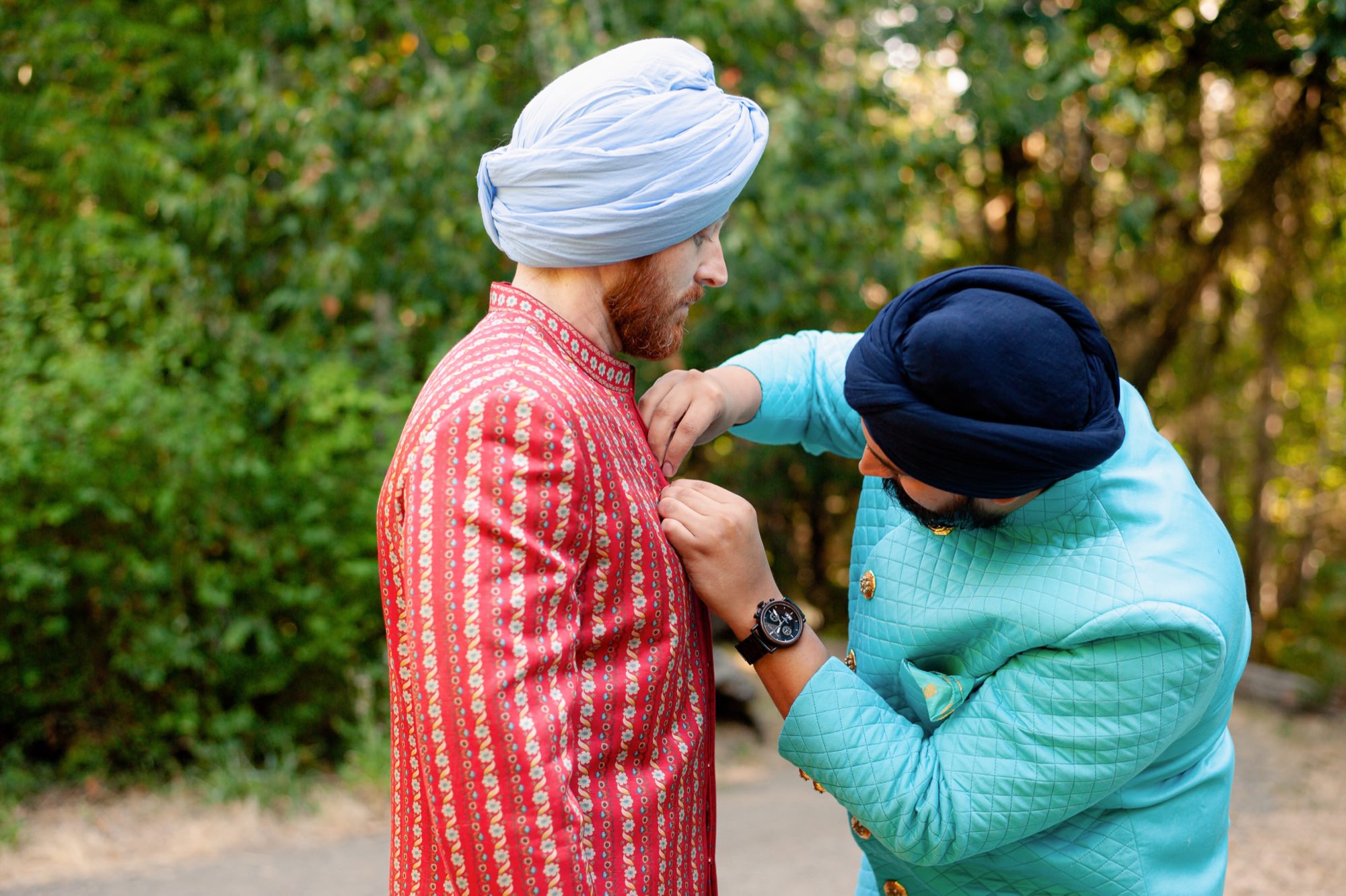 Groom receiving help with his traditional outfit