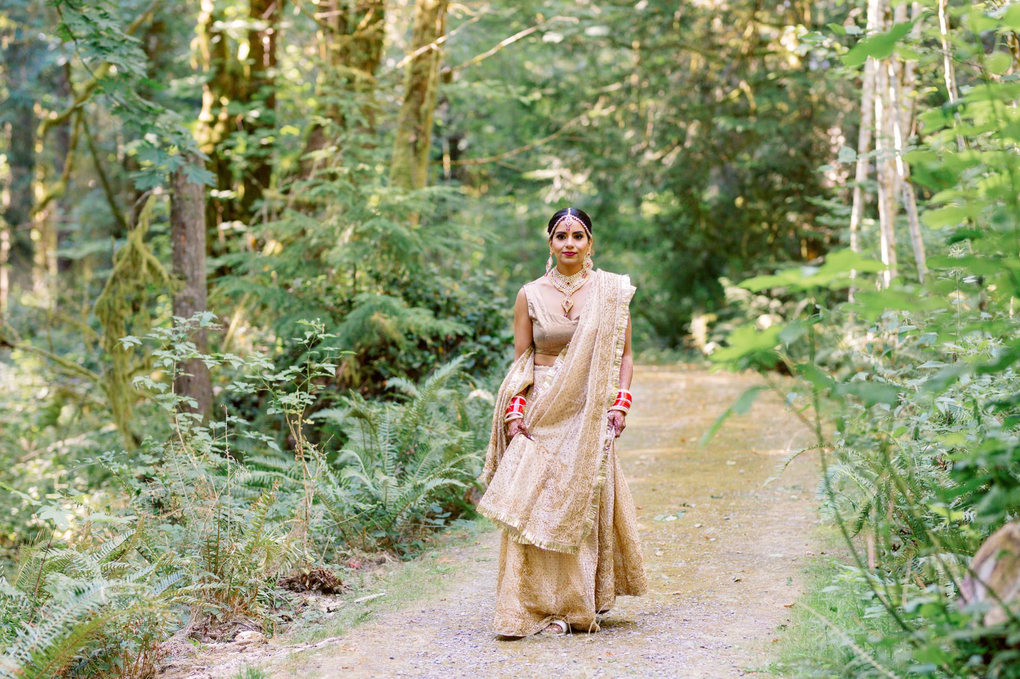 Bride walking through the woods in her golden lehenga