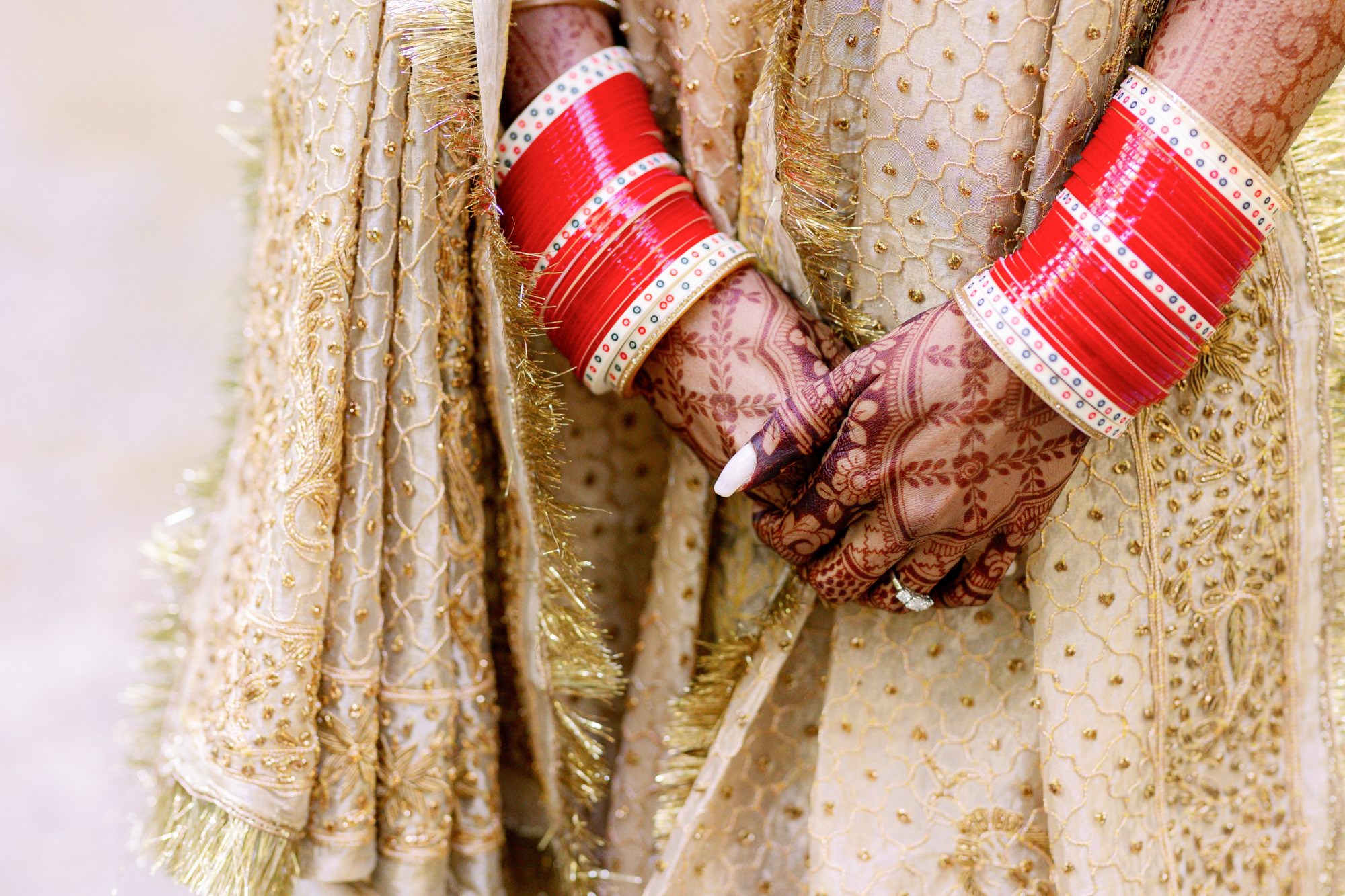 Close-up of bride's hands with henna and red bangles