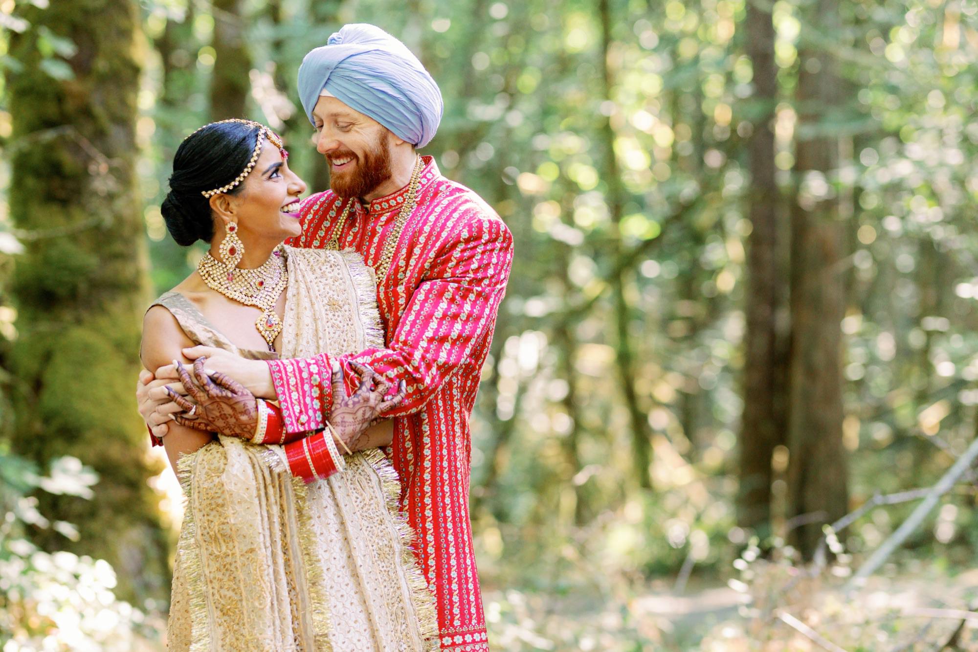 Bride and groom smiling and embracing in the woods