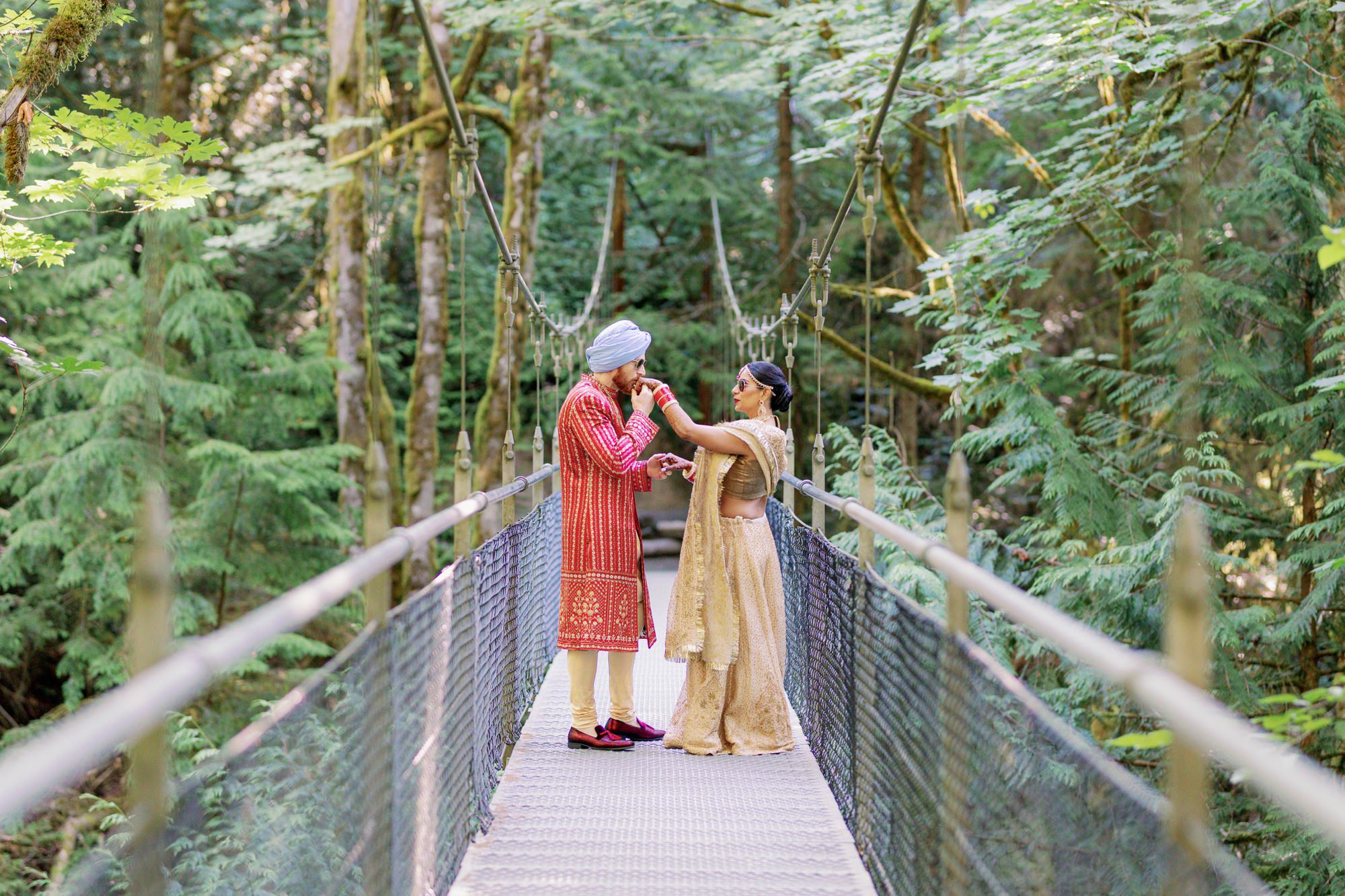 Couple sharing an intimate moment on a forest bridge during their Indian wedding.