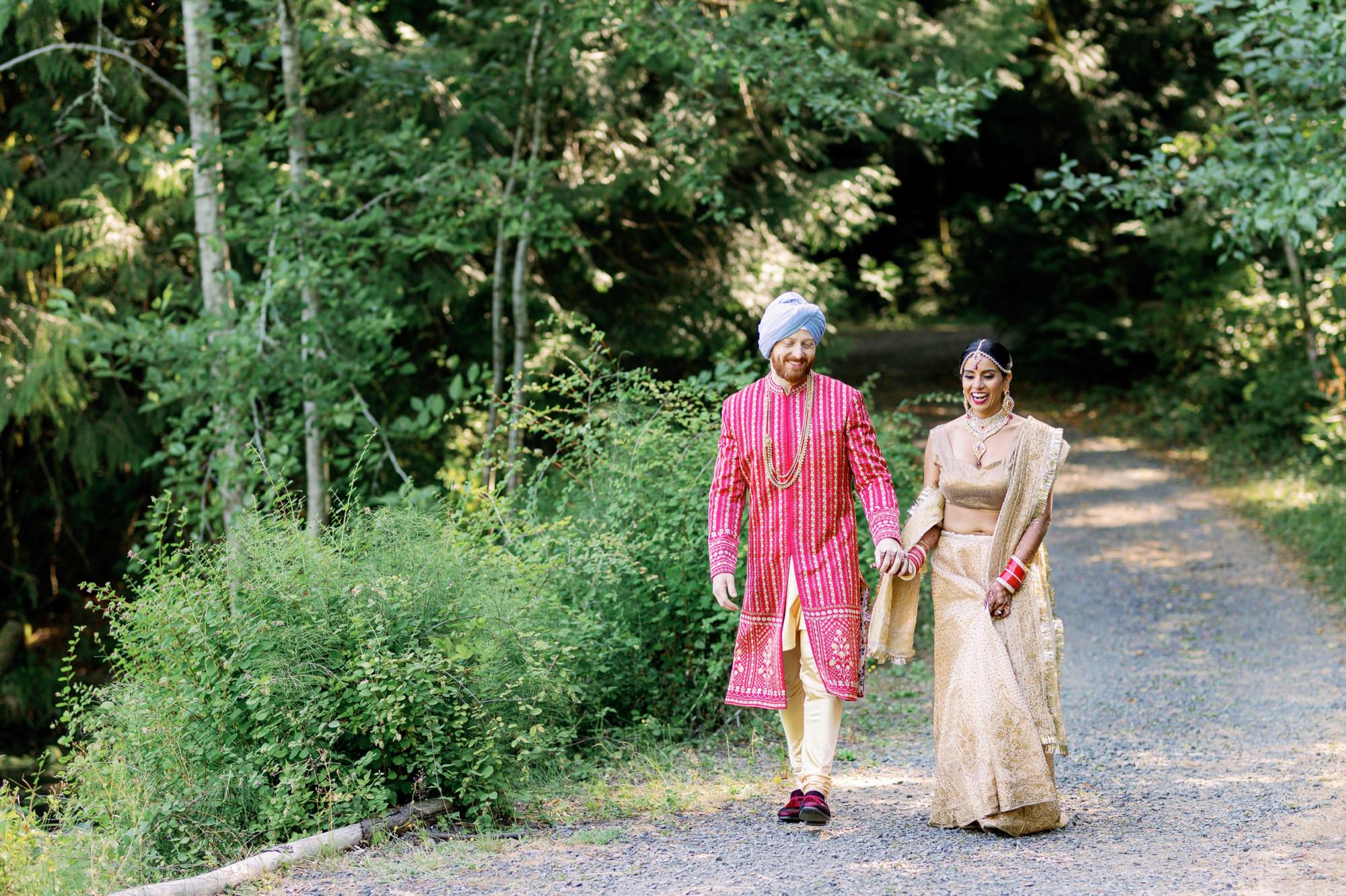 Couple walking hand-in-hand on a forest path during their Indian wedding.