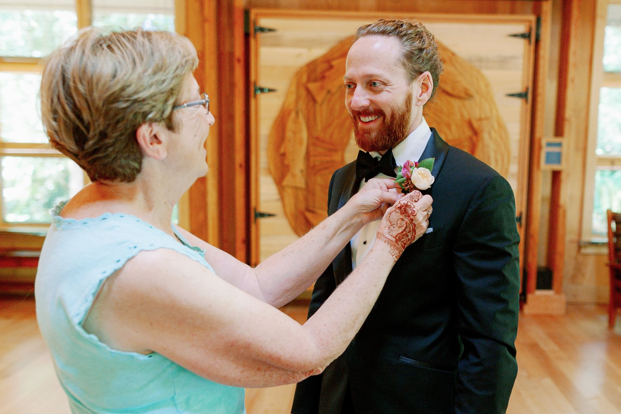 Groom's boutonniere being adjusted by a family member before the wedding ceremony.