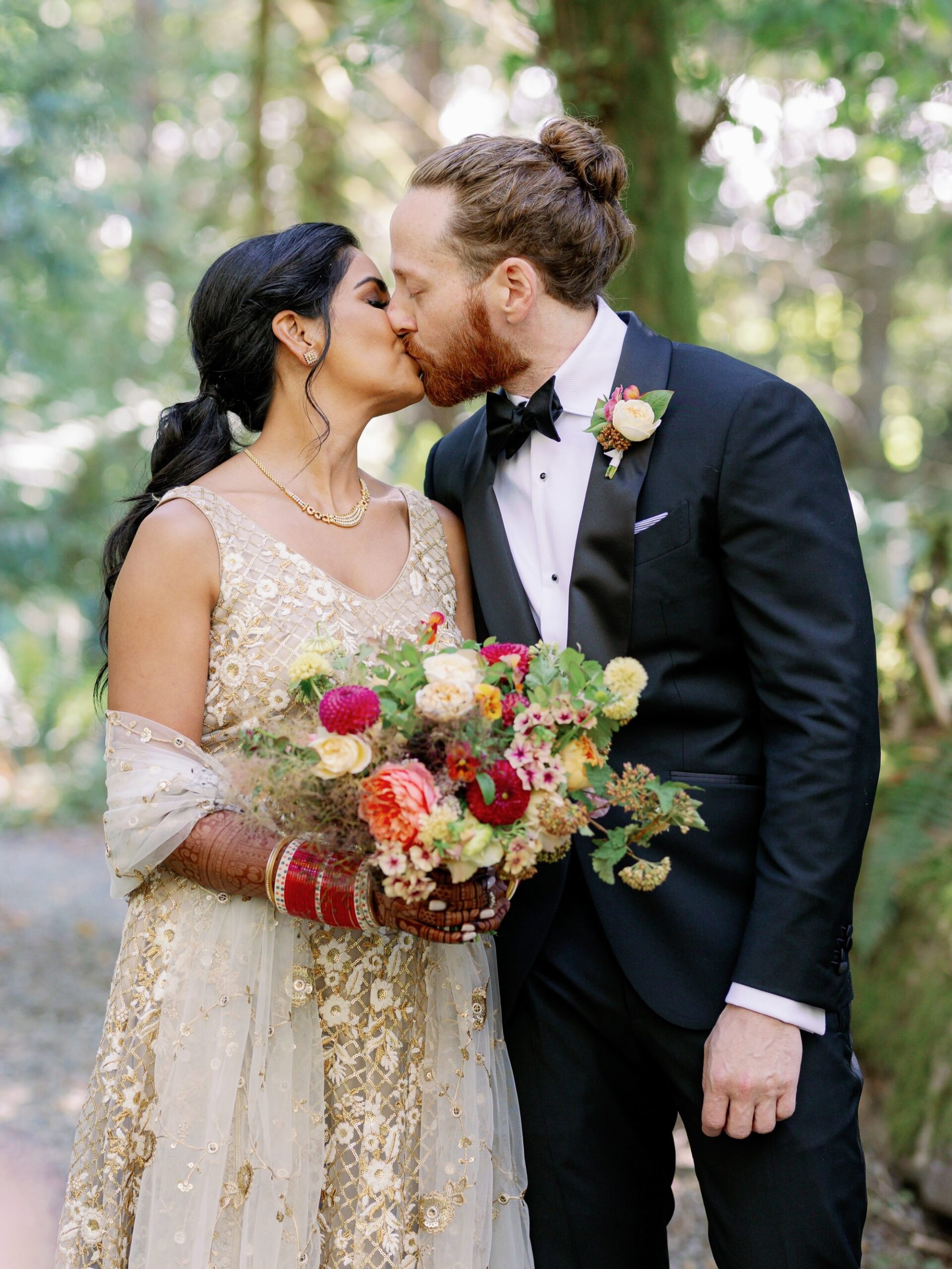 Couple sharing a kiss in the forest during their multicultural wedding at IslandWood.