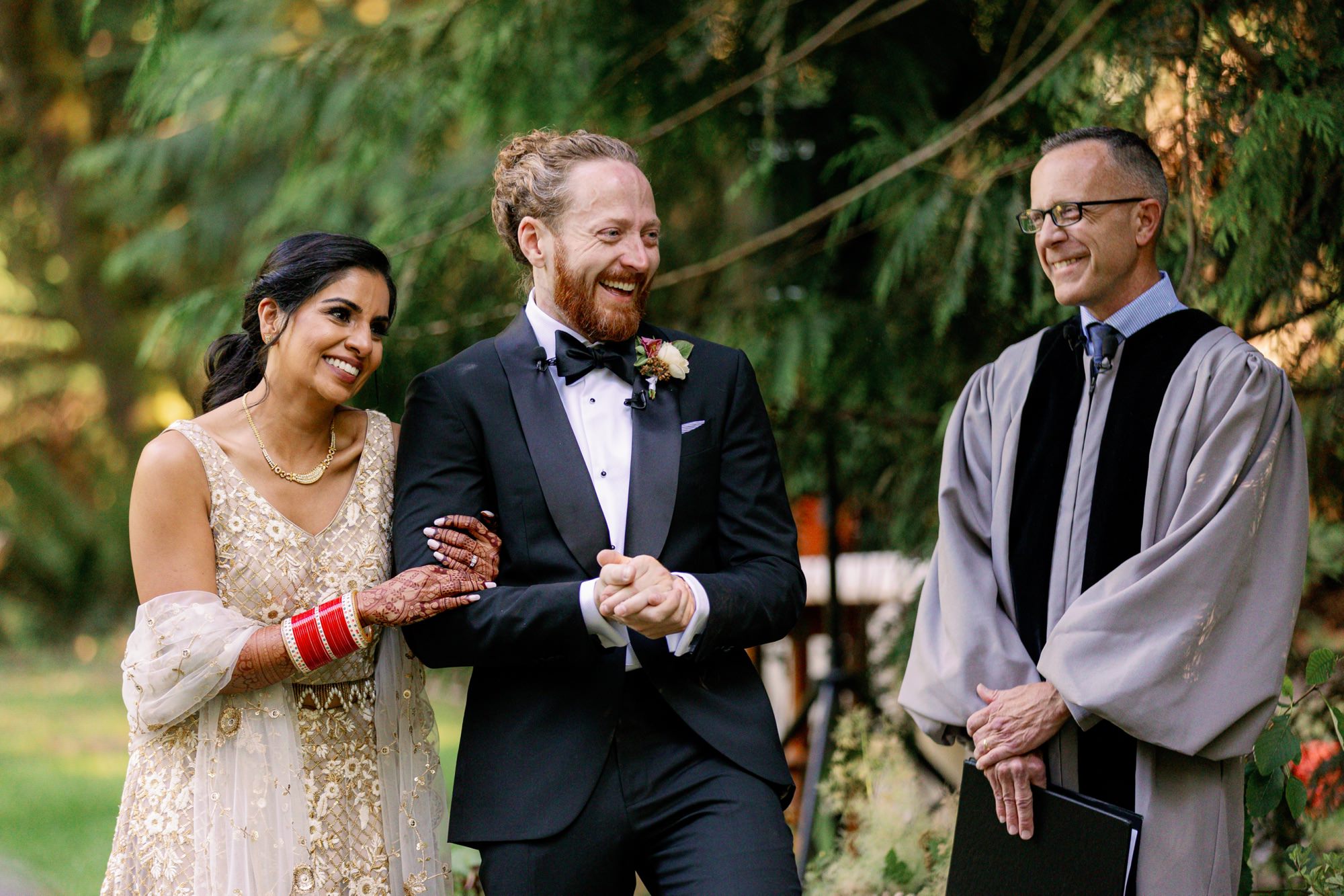 Bride and groom sharing a joyful moment with the officiant.