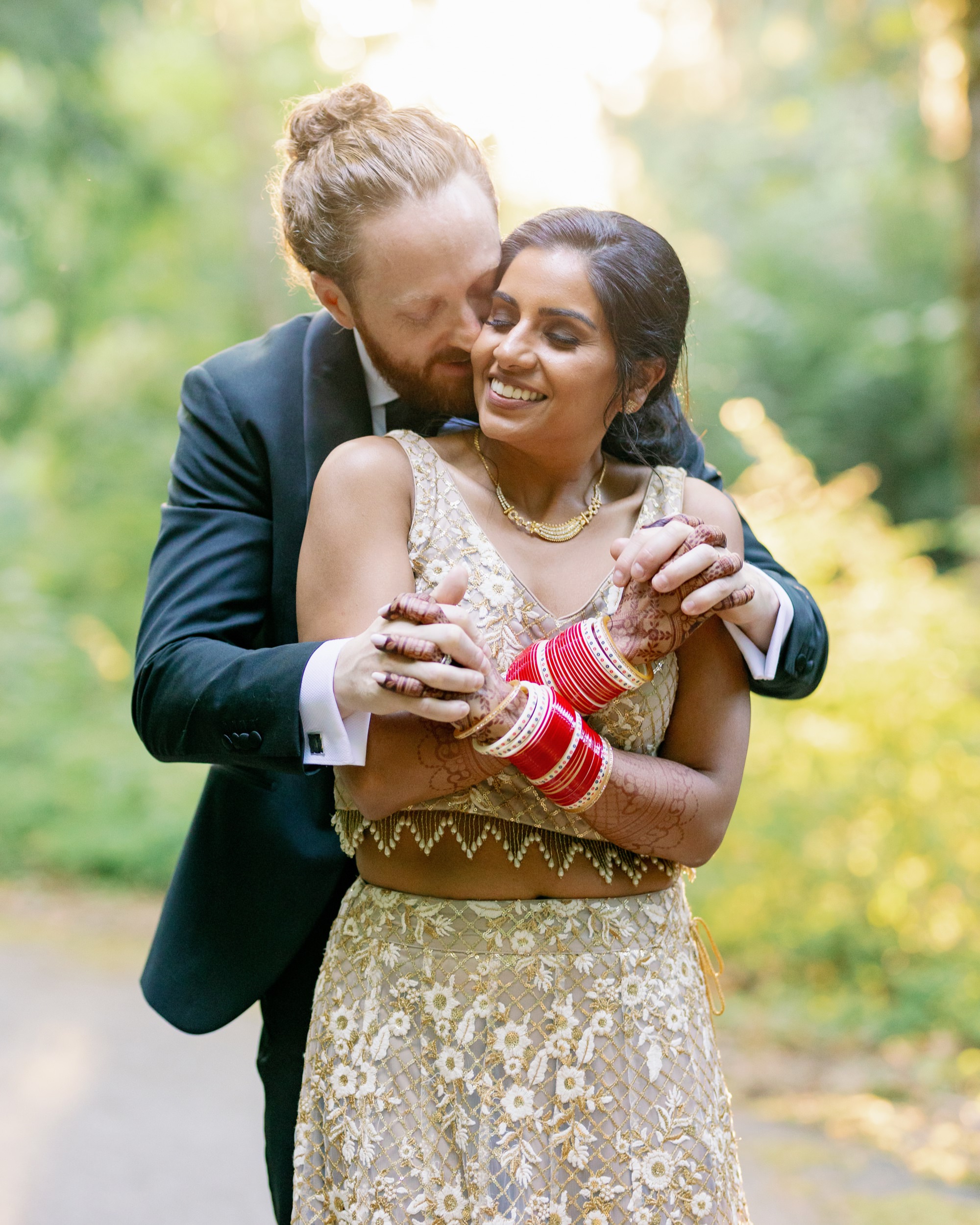 Close-up of groom kissing the bride while cuddling from behind.