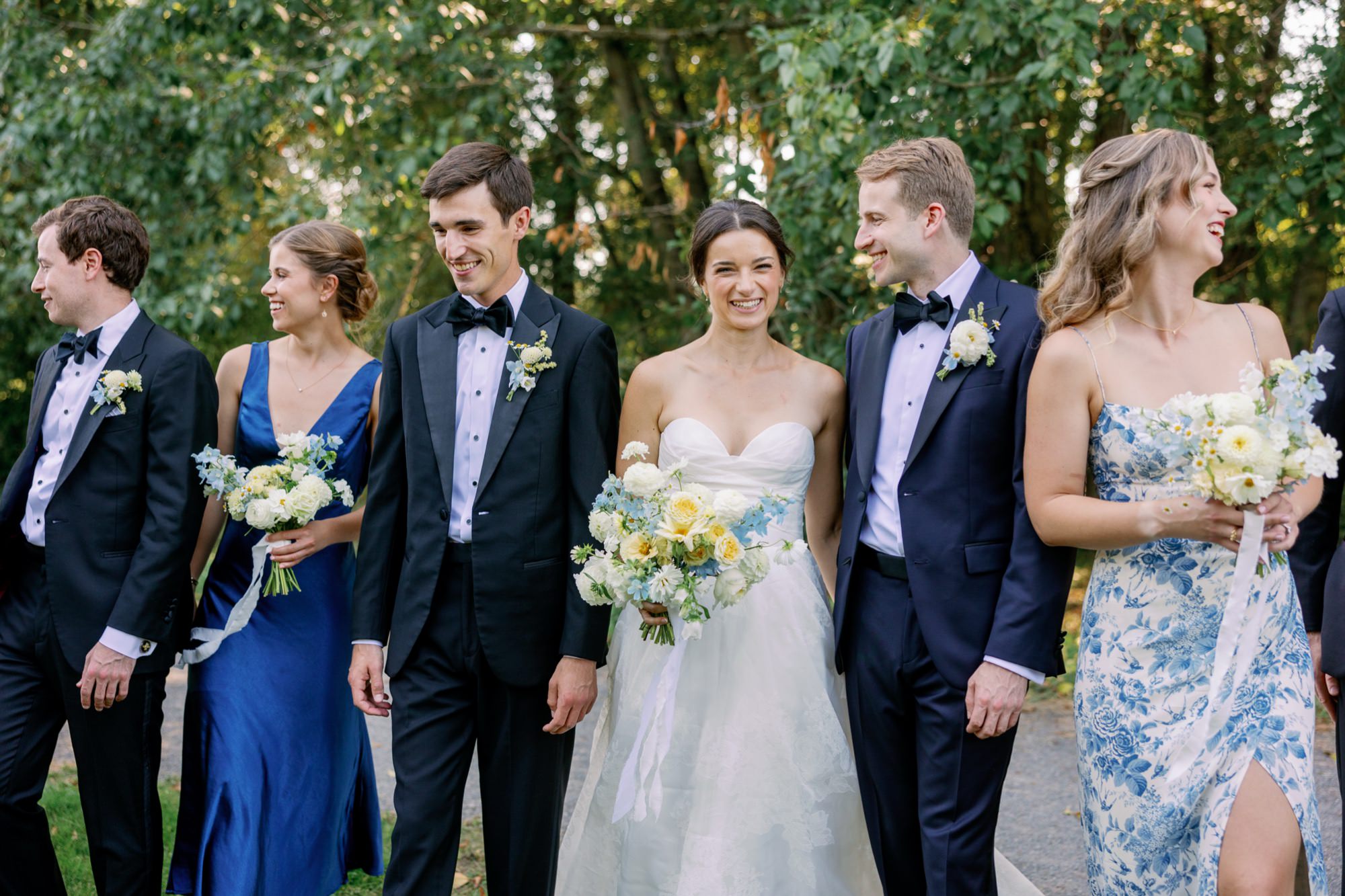 The wedding party gathers close for a relaxed portrait in the gardens.”