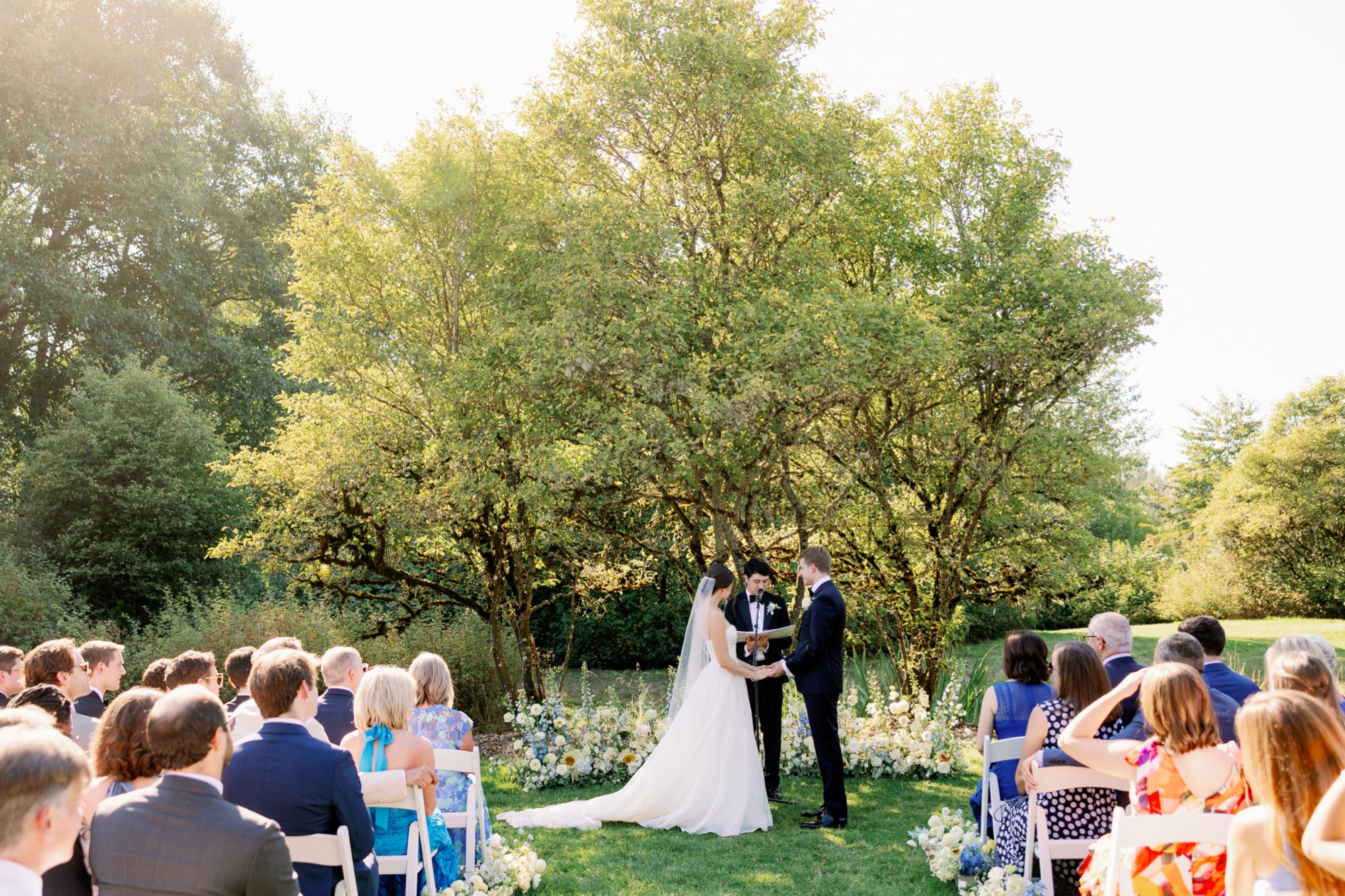 Wedding ceremony taking place on the lawn at the Center for Urban Horticulture surrounded by greenery.