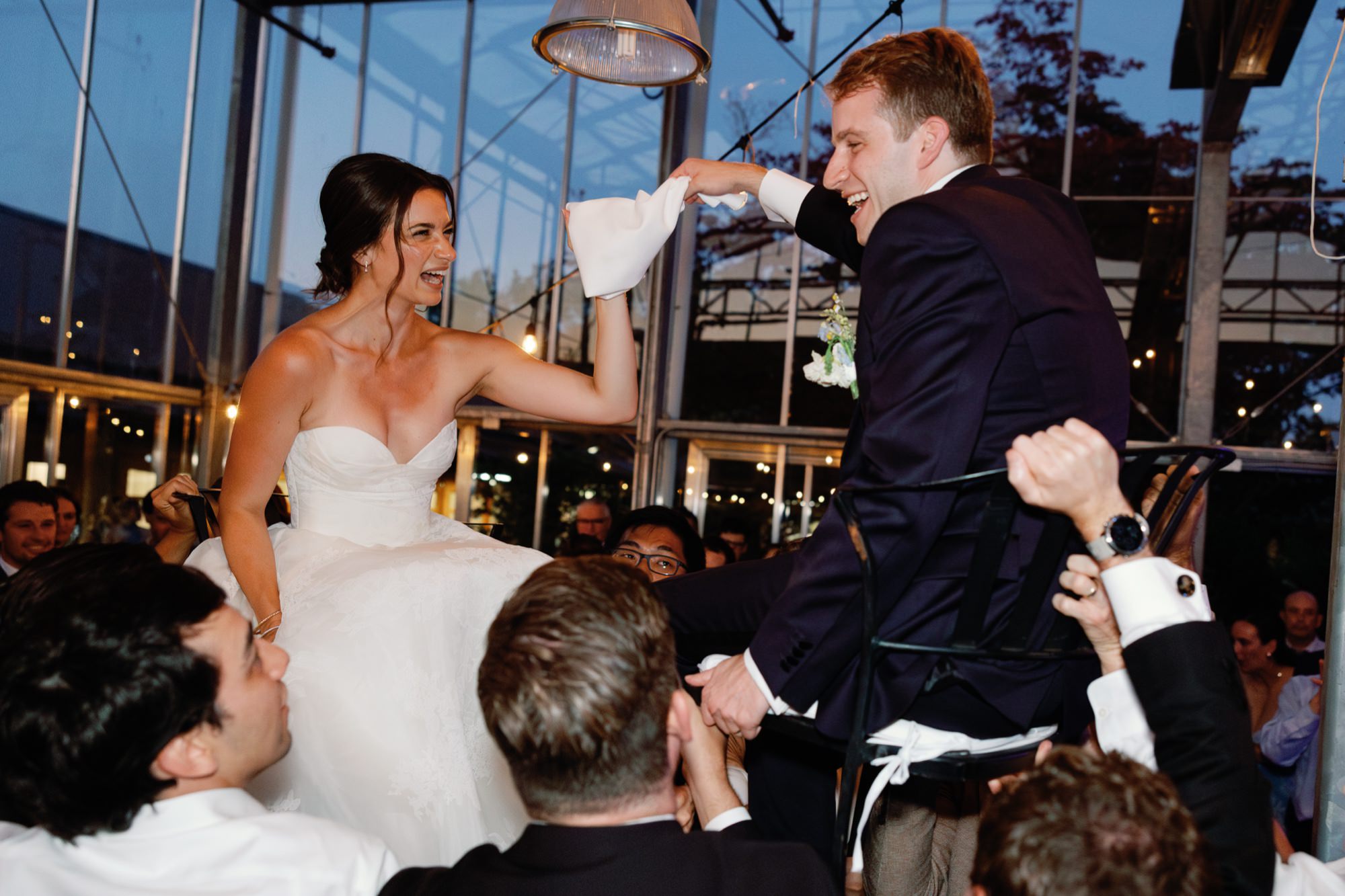 Guests lifting the couple in chairs during the hora.