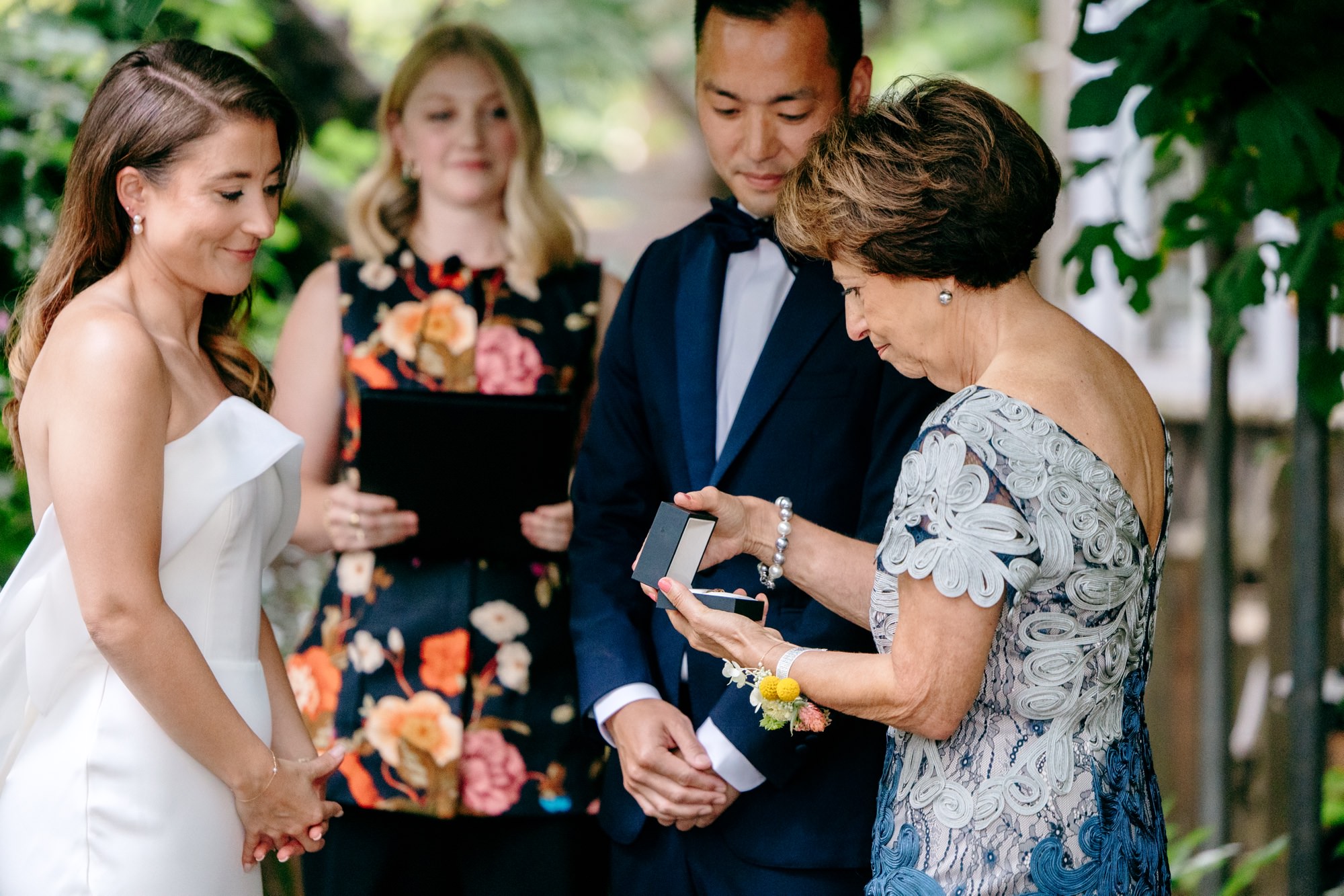 The bride's mom delivers the wedding rings to the couple before they exchange rings.