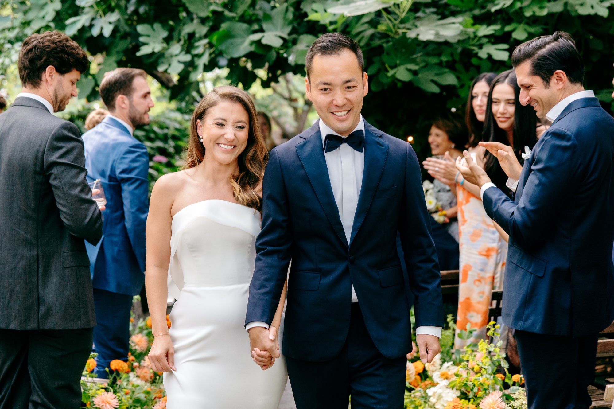 wedding guests clap as the bride and groom exit the ceremony