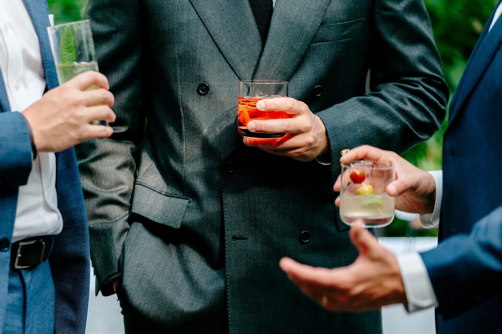 Guests hold colorful drinks during cocktail hour