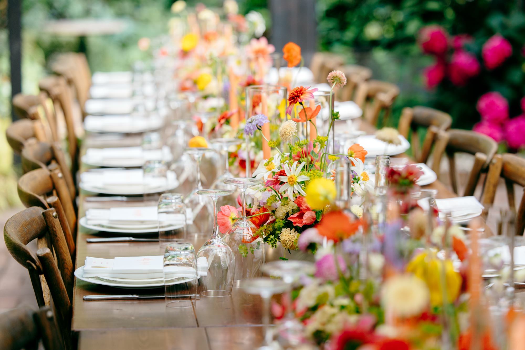 Long communal dinner table at The Corson Building, decorated with bright florals for an intimate wedding