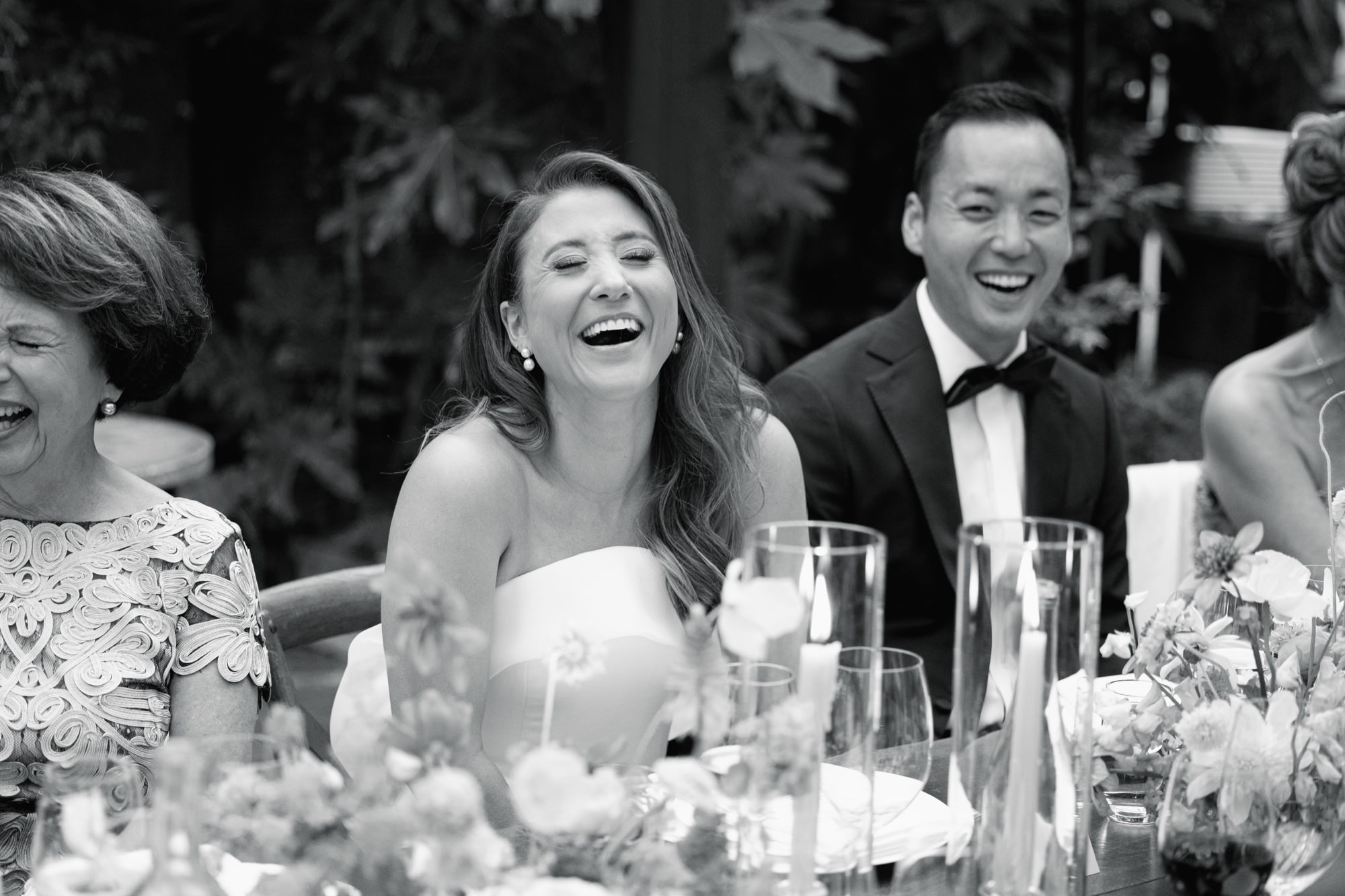The bride and groom react and laugh during a speech.