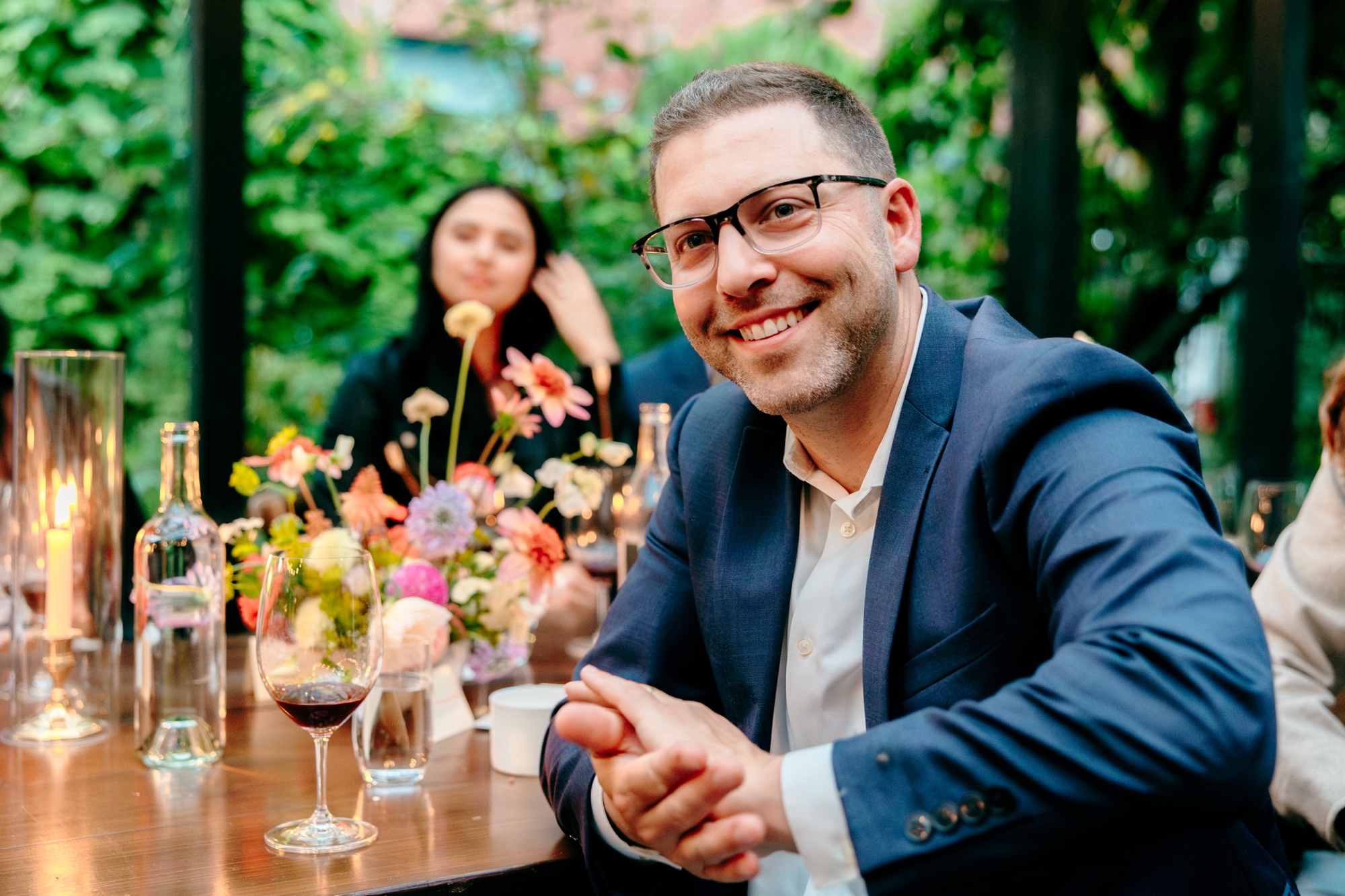 A wedding guest smiles and claps after a speech.