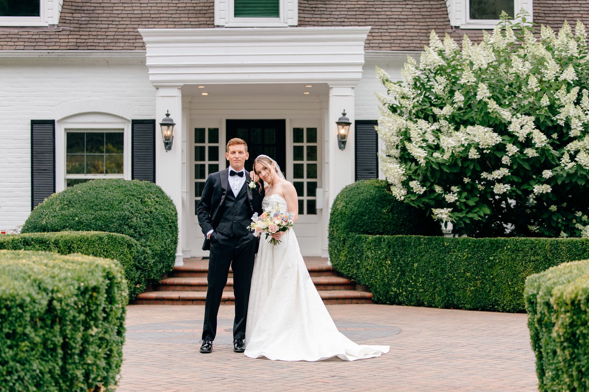 Wedding couple standing in front of the historic manor at Fox Hollow Farm, a picturesque Seattle wedding venue with charming architecture and lush surroundings.