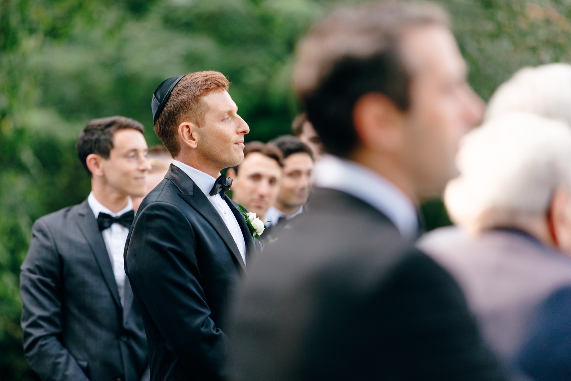 Groom watching his bride walk down the aisle with greenery in the background at Fox Hollow Farm.