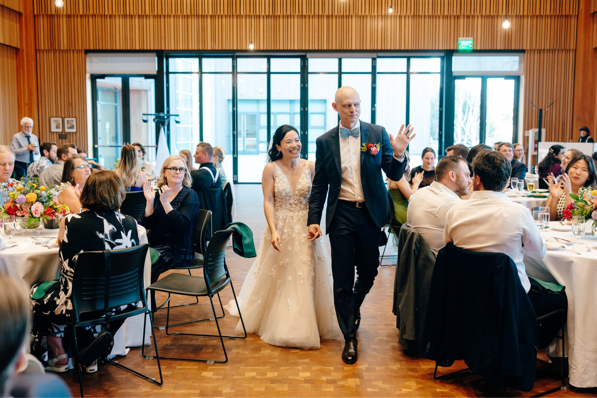 The couple enters their wedding receptions while guests clap.